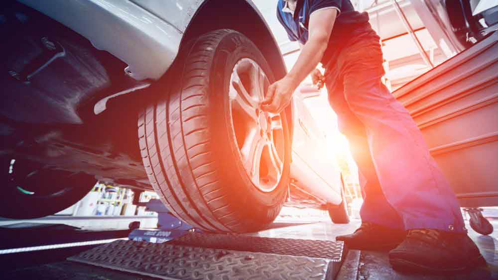 Car on lift being services with sun in background - Advanced Auto Solutions Collision Repair Services