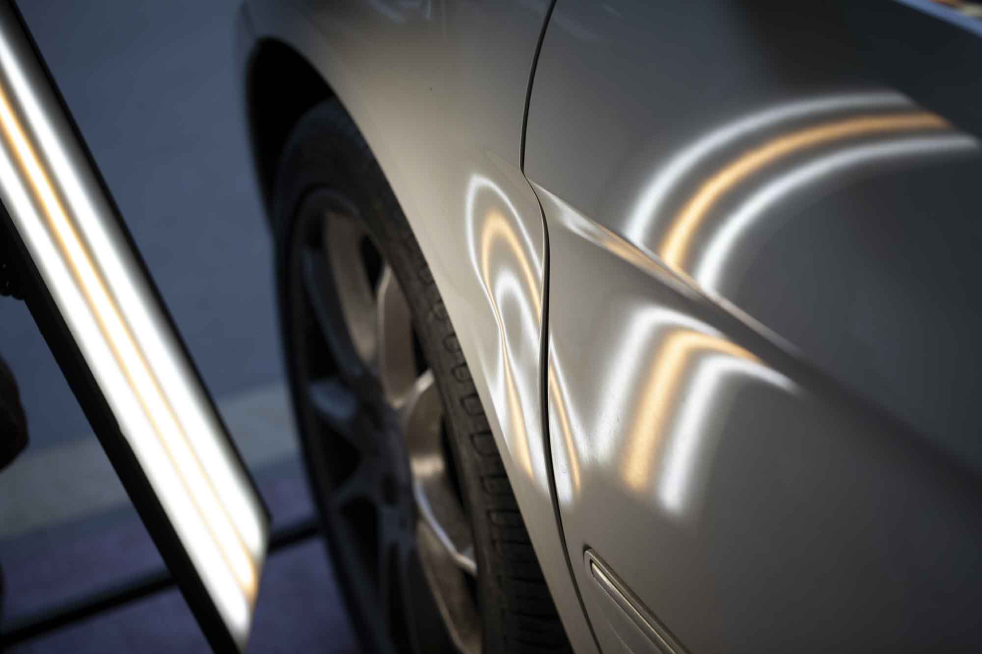 Performing paintless dent repair on silver sedan - Advanced Auto Solutions collision repair services 