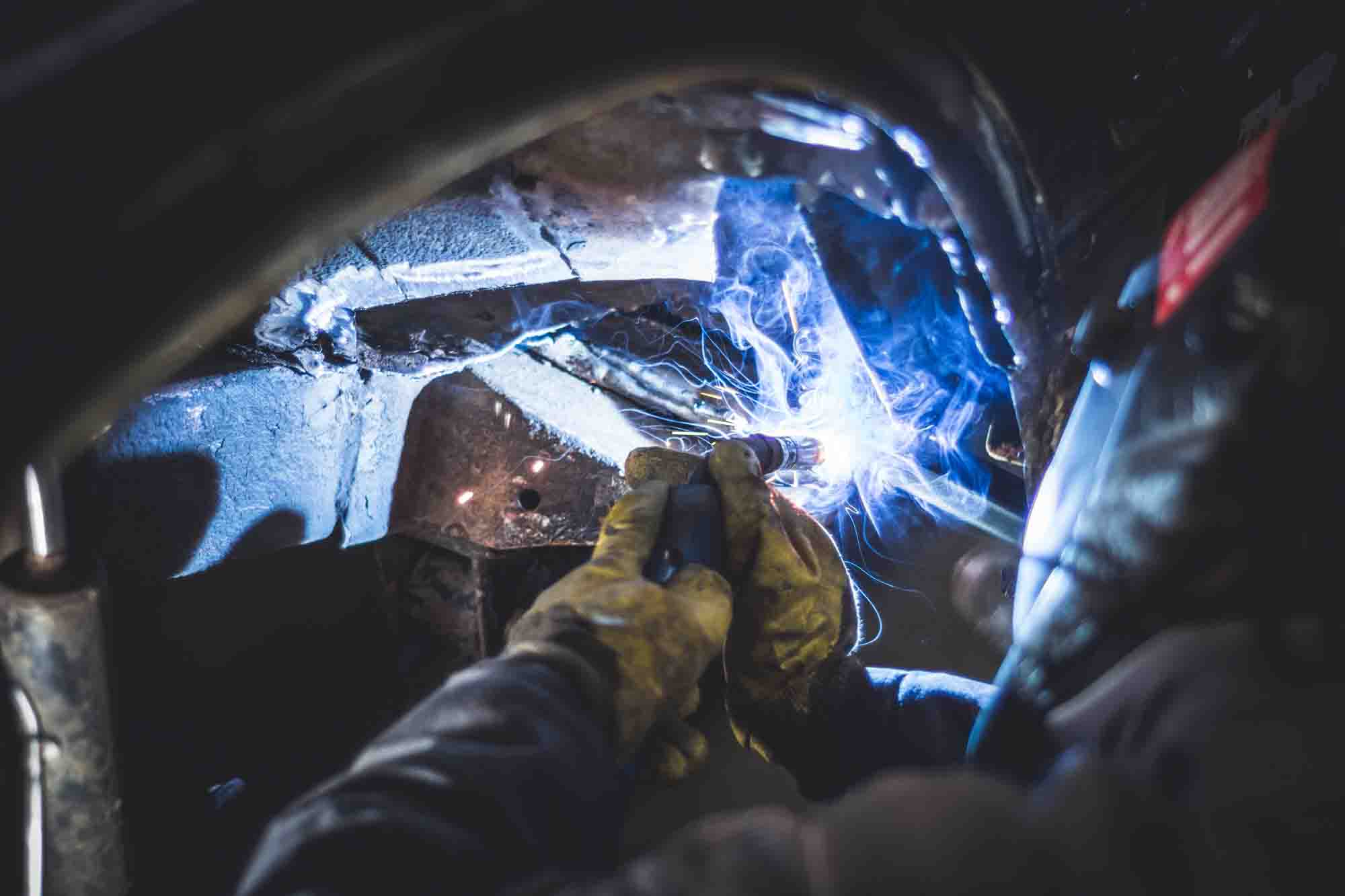 Technician welding in wheel well of vehicle - Advanced Auto Solutions collision repair services 
